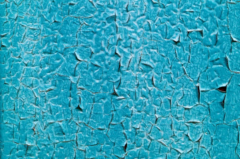 Detailed image of cracked turquoise paint creating a unique abstract texture.